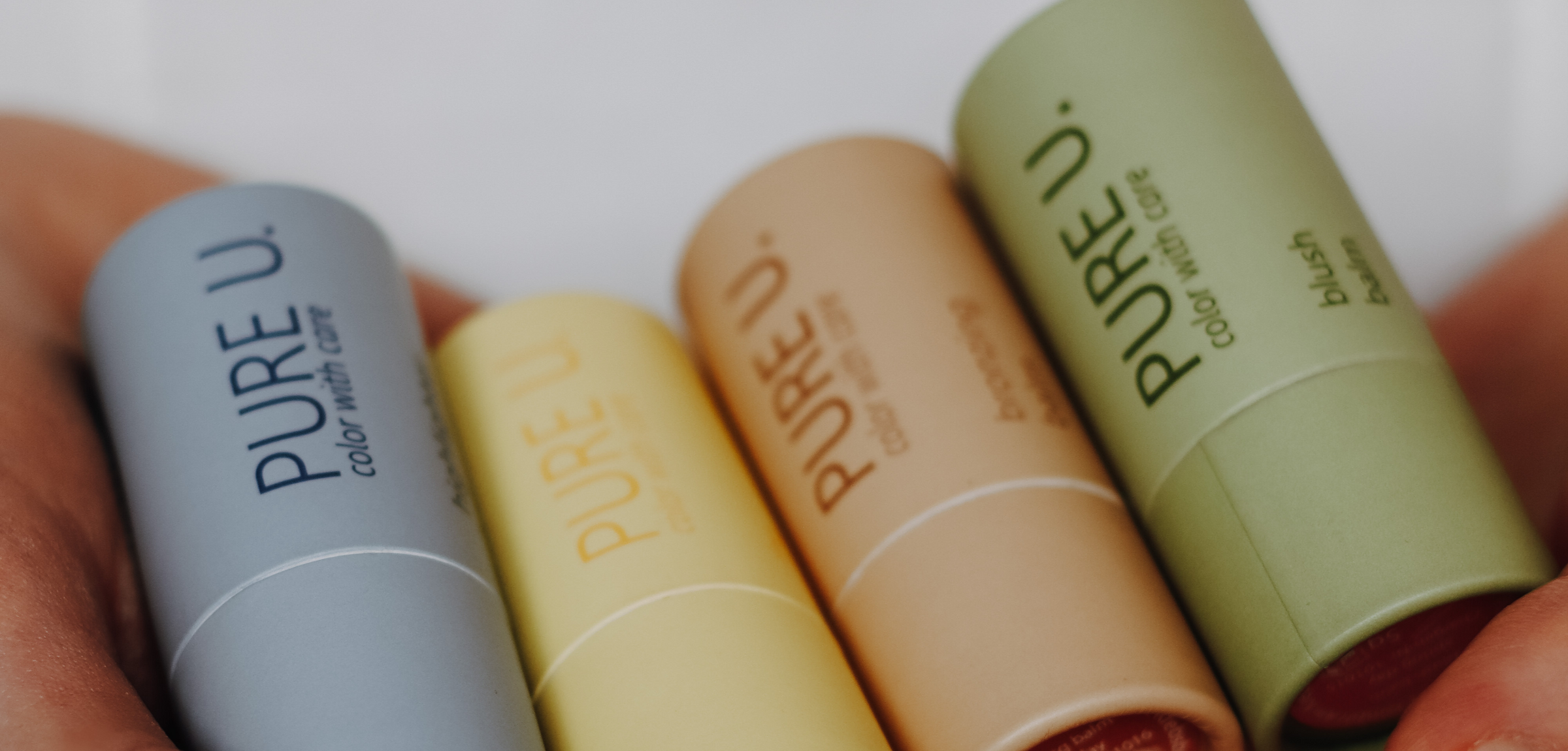 Eine Hand hält die PURE U. Make-up Produkte in die Kamera