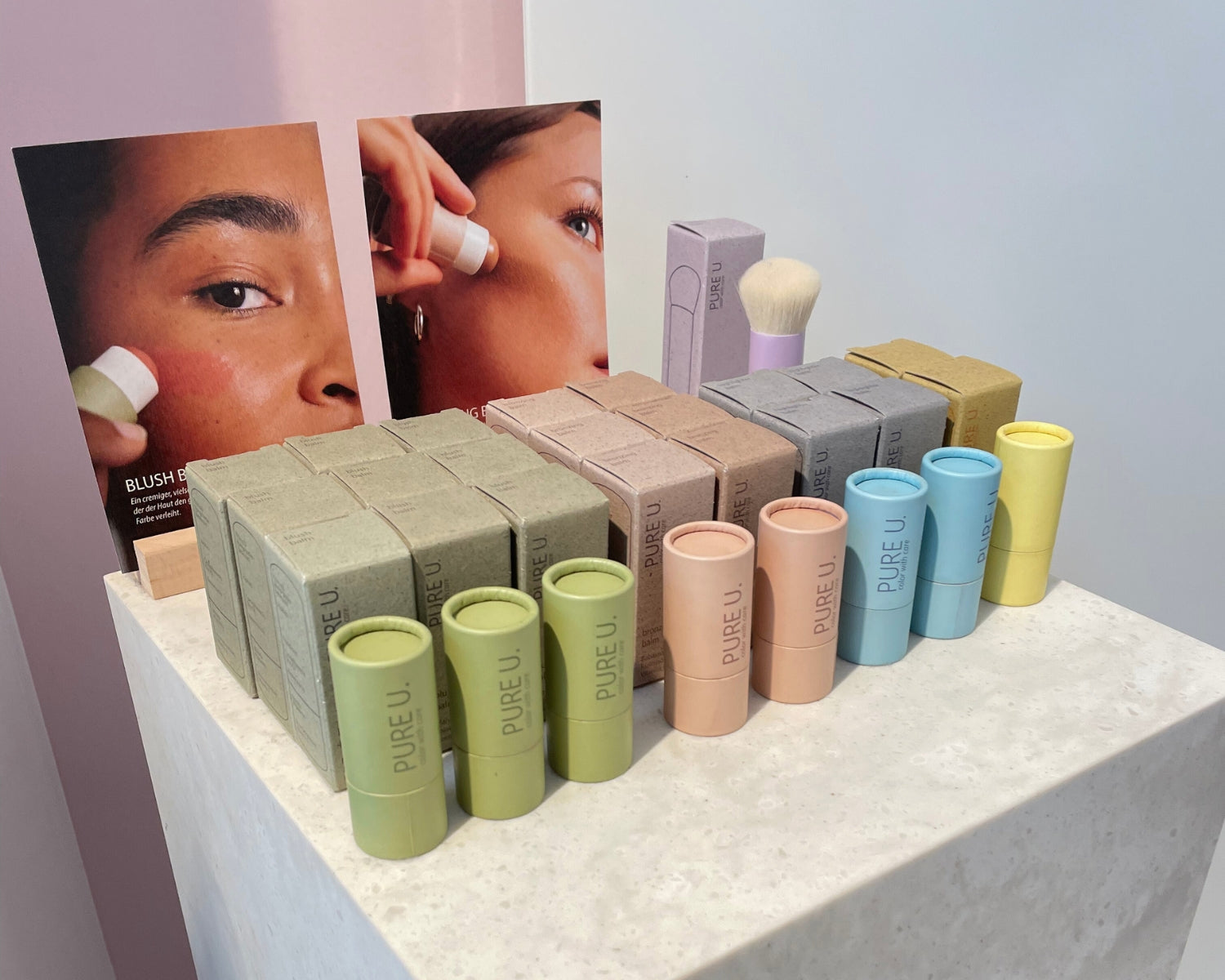 Make-up Produkte von PURE U. stehen ausgestellt auf einer Säule in einem Laden mit Aufstellern